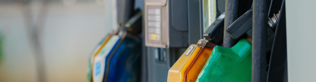 Close-up of fuel pump nozzles in various colors at a gas station.