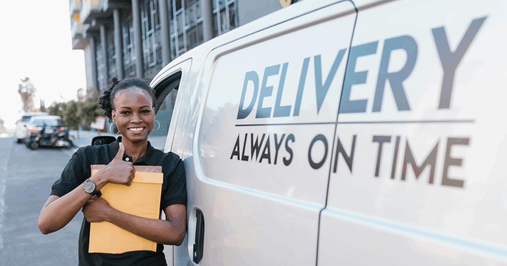 A happy employee stands in front of a van.