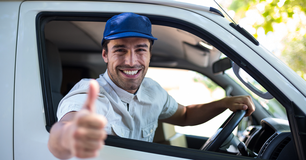 A happy smiling driver is looking out of the window and gives a thumbs up