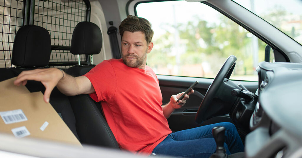 Van driver in a red top is reaching for a parcel